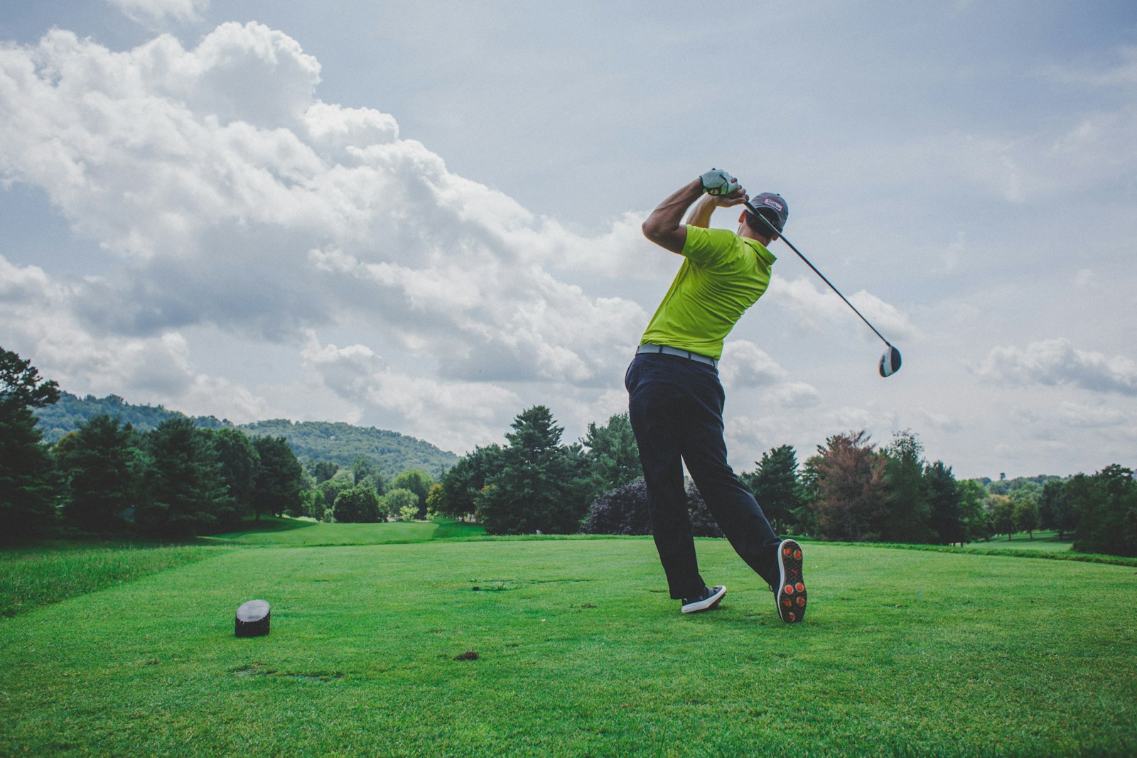 Golfer finishing a swing on a green course beneath a bright sky